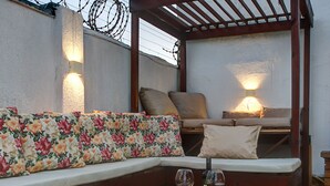 A rooftop terrace with a wooden bench, a cushioned sofa, and a small table with wine glasses. - Casa 25pessoas c piscina Porto das Dunas (Aquiraz)