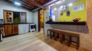 A kitchen with wooden cabinets, a tiled backsplash, and a bench. - Casa 25pessoas c piscina Porto das Dunas (Aquiraz)