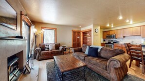 A cozy living room with a fireplace, a wooden coffee table, and two leather sofas. - Quiet Forest Setting. Near The Village & Lake Basin, Pool & Hot Tub On-site (Mammoth Lakes)