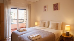 A hotel room with a large bed, two bedside lamps, a window with curtains, and artwork on the wall. - FLH Cascais Wooden Spacious Apartment (Cascais)