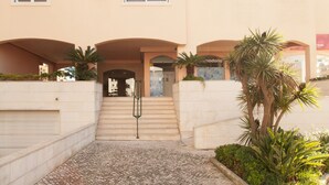 A building with a central entrance, a staircase leading to the entrance, and a palm tree in the foreground. - FLH Cascais Wooden Spacious Apartment (Cascais)