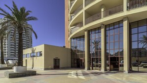 A modern building with large windows, a flat facade, and a balcony with railings.