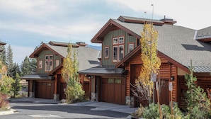 A row of log cabin-style buildings with a central driveway and a parking area. - Remodeled & Beautiful Home. Private Hot Tub & Gas Grill, Near Biking Trails (Mammoth Lakes)