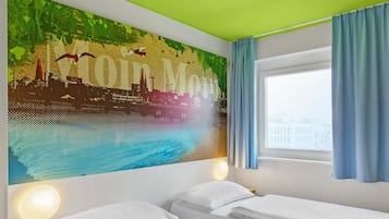 Ein Hotelzimmer mit zwei Betten, einer Stadtlandschaft-Mural, einer grünen Decke und einem mit Vorhängen versehenen Fenster.