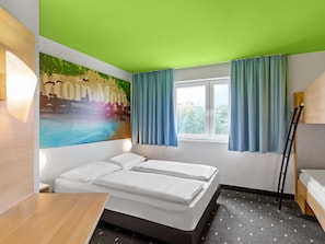 Une chambre d’hôtel avec un lit, une fenêtre avec des rideaux, un mur orné d’une fresque représentant un paysage urbain, et une échelle.