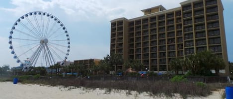 Un hotel frente a la playa con una noria al fondo.