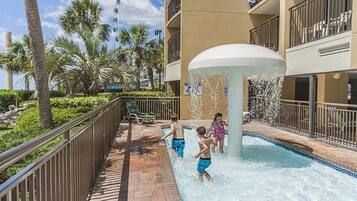 A pool area with a water feature, palm trees, and a Ferris wheel in the background.