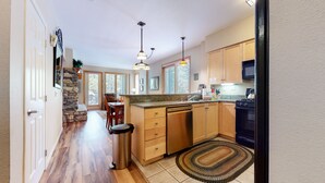 A modern kitchen with wooden cabinets, a granite countertop, a stainless steel sink, and a black stove.