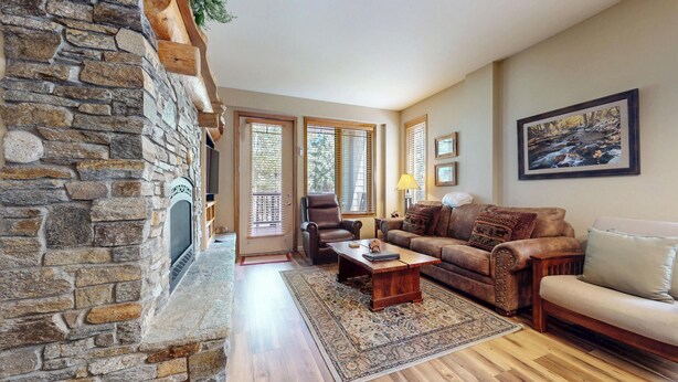 A living room with a stone fireplace, a leather armchair, a sofa, and a large painting on the wall.
