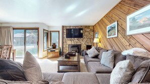 A cozy living room with a stone fireplace, a large flat-screen TV, and a comfortable sofa set.