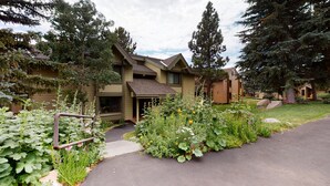 A two-story house with a sloped roof, surrounded by a garden with various plants and flowers. - Pet-Friendly Quiet Corner Cabin, Relaxing Location. Near Beautiful Trails (Mammoth Lakes)