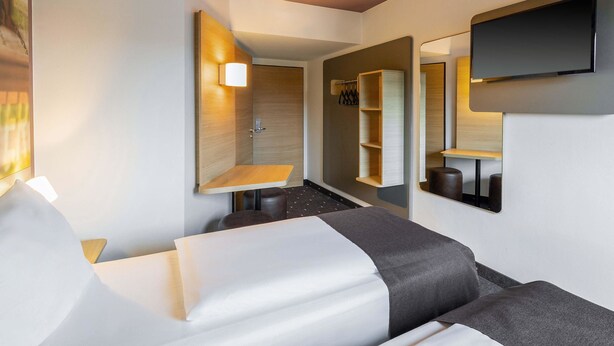 Een moderne hotelkamer met een bed, een zithoek, een spiegel en een televisie.