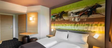 Una habitación de hotel moderna con una cama grande, un escritorio y un televisor de pared mostrando una carrera de caballos.