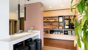 Een moderne keuken met een wit aanrecht, zwarte krukken en diverse etenswaren.