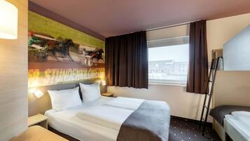 Ein Hotelzimmer mit einem Bett, einem Schreibtisch, einem Stuhl, einem Fenster mit Vorhängen und einem Wandbild.