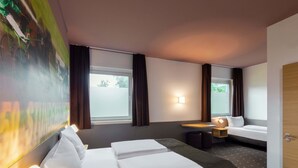 Een hotelkamer met een bed, een tafeltje, een bank en een schilderij aan de muur.