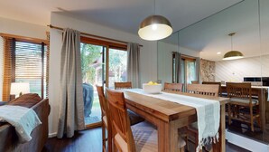 A modern dining area with a wooden table, chairs, and a large mirror. - Pet-Friendly. Updated, Private Gas Grill, Located in the Quiet Meadow Area (Mammoth Lakes)