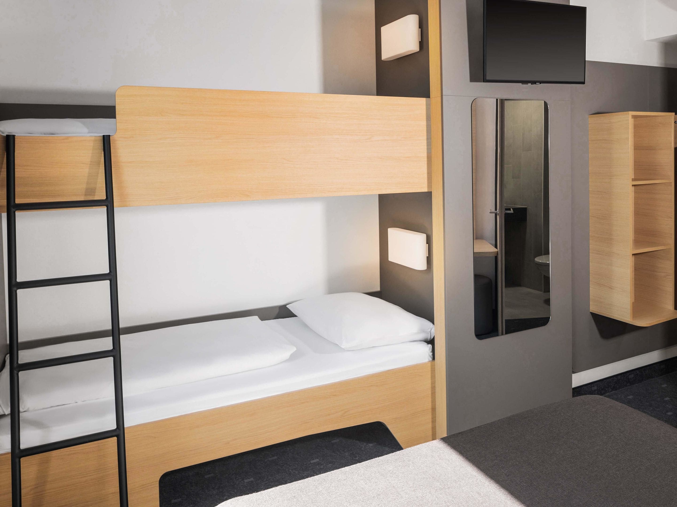 Ein Etagenbett mit einer Leiter, ein Nachttisch, ein Spiegel und ein kleiner Schrank.