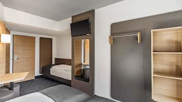 A compact hotel room with a bed, a desk, and a wardrobe.