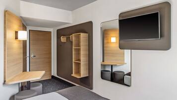 Una habitación de hotel moderna con cama, escritorio, espejo y televisor.