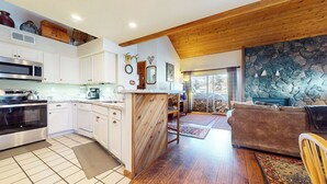Una cocina moderna con armarios blancos, una isla grande y una chimenea de piedra.