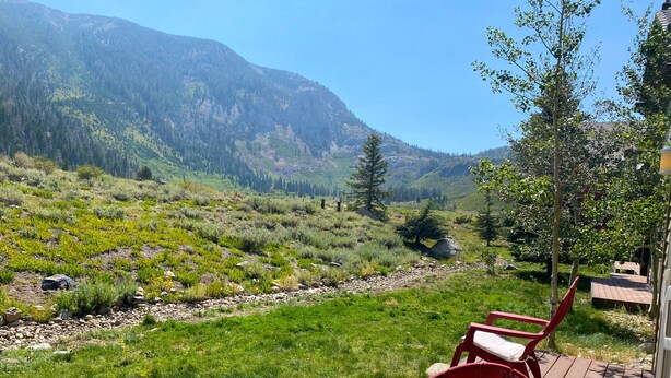 Une terrasse avec des chaises rouges donnant sur un paysage montagneux.