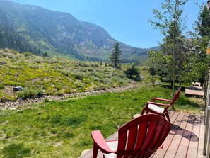 Une terrasse avec des chaises rouges donnant sur un paysage montagneux.