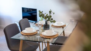 A dining table set with plates, glasses, and a vase with a plant. - Walker Suite No53 - Donnini Apartments (Kilmarnock)