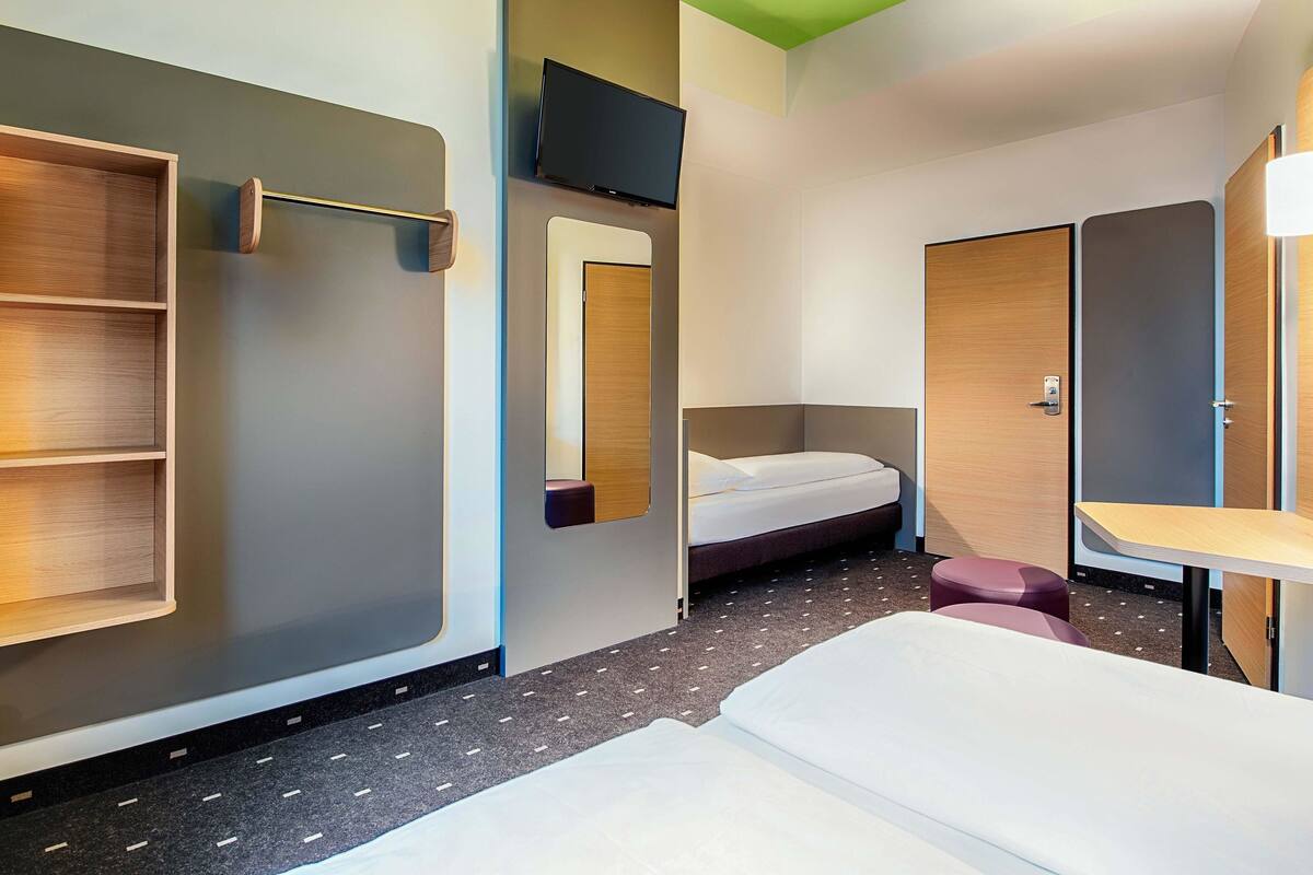 Une chambre d’hôtel moderne équipée d’un lit, d’un bureau, d’un miroir et d’une télévision.