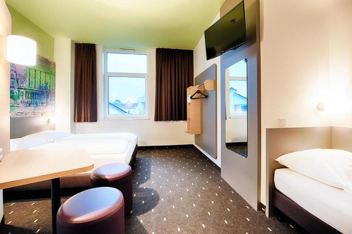 Une chambre d’hôtel avec deux lits, un bureau et une télévision.