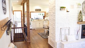 Une cuisine spacieuse avec des meubles blancs, un escalier en bois et une cheminée.