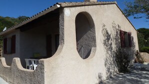 A rustic building with a sloped roof, a chimney, and a large arched window. - Detached villa 4/6 persons 3 terraces - Palombaggia magnificent sea view (Porto-Vecchio)