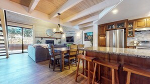 Una cucina moderna con mobili in legno, un'isola grande e un'area pranzo con divano e sedie.