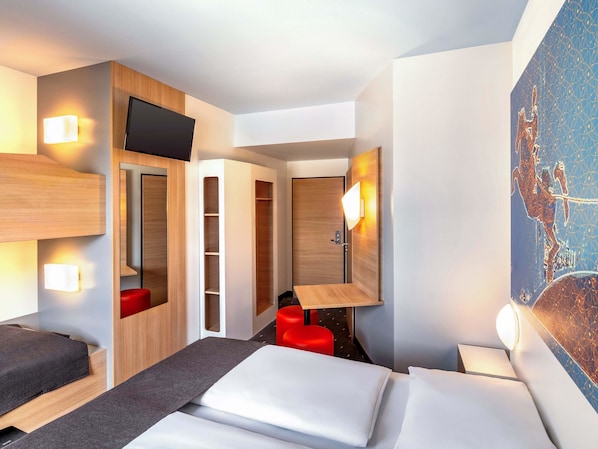 A modern hotel room with a bed, a desk, a red chair, and a TV. - B&B Hotel Magdeburg-City (Magdeburg)