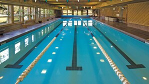 Une grande piscine intérieure avec des couloirs clairement délimités, des murs en bois et des plantes en pot disposées le long des bords.