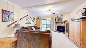 Un salon chaleureux avec une cheminée, des meubles en bois et un ventilateur de plafond.