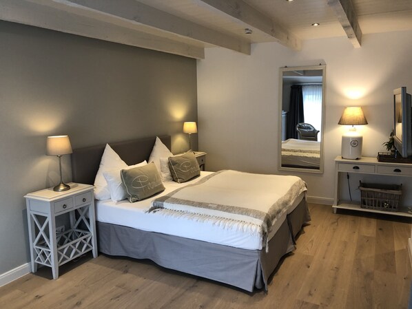 Un dormitorio moderno con una cama grande, lámparas de noche, un tocador y un espejo.