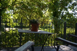 A wooden deck with a metal railing, a potted plant, and a bench. - Hotel Leegerpark (Krummhoern)