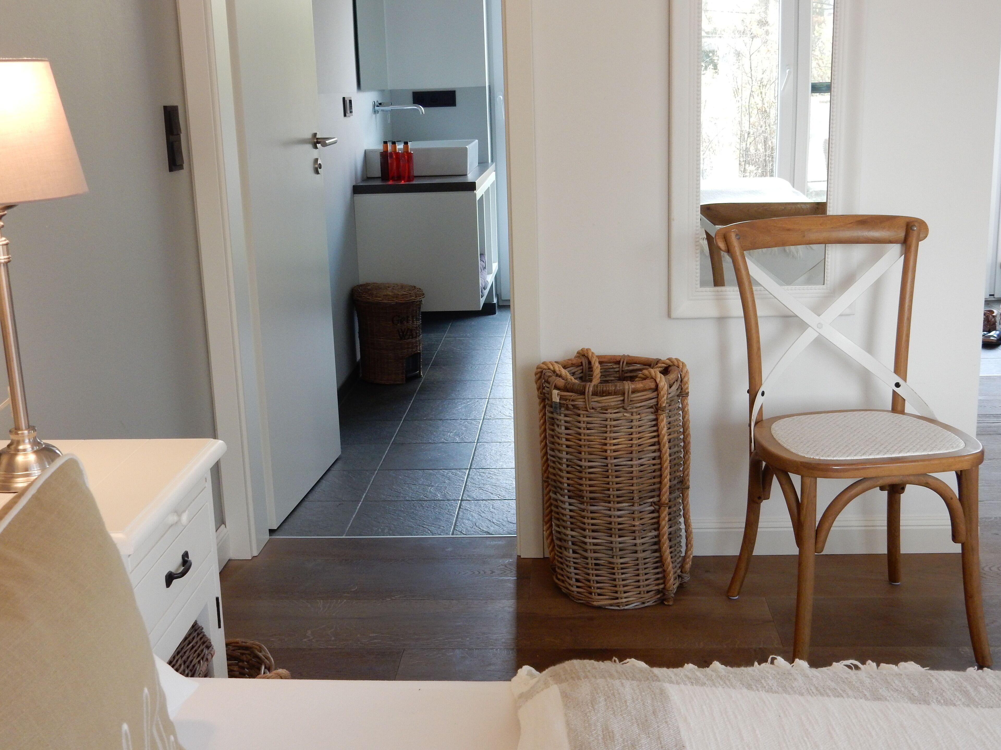 Ein Schlafzimmer mit einem Bett, einem Korbwäschesessel, einem Holzstuhl und einem Nachttisch.