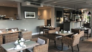 Un restaurante moderno con mobiliario de mimbre, una zona de bar y una amplia pantalla de televisión.