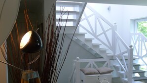 Un interior moderno con una escalera, una lámpara y un banco blanco.