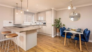 Une cuisine moderne avec un îlot central, des tabourets de bar, une table à manger avec des chaises et un grand miroir rond au mur.