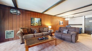 A cozy living room with two sofas, a coffee table, and wooden panel walls. - Spacious Condo near Walking Trails. Pool, Hot Tubs & Tennis Court On-site (Mammoth Lakes)