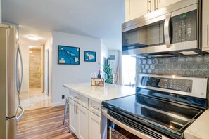 Enjoy cooking in this well-lit kitchen with a sleek countertop, microwave, and oven.