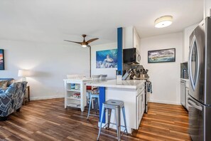 Una cocina moderna con una isla central, electrodomésticos de acero inoxidable y un ventilador de techo.