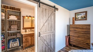 A room with a wooden wardrobe, a mirror, a bed, and a wardrobe with a sliding door. - Oceanfront Penthouse Vistas (Kihei)