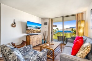Relax in this stylish living room with a flat-screen TV, comfortable sofa, and a beautiful view of the coastal landscape.