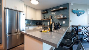 Una cocina moderna con electrodomésticos de acero inoxidable, encimera de mármol y un enfriador de vinos empotrado.
