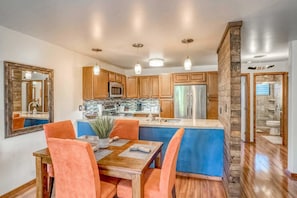 A modern kitchen with wooden cabinets, a central island, and pendant lighting.