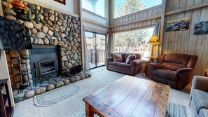 Relax in this inviting living room with a fireplace, comfortable seating, and a large window offering a view of the outdoors.